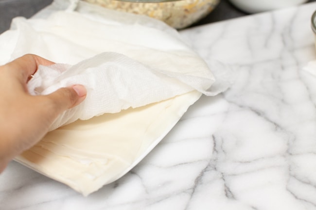 egg roll wrappers on a plate covered with a damp paper towel