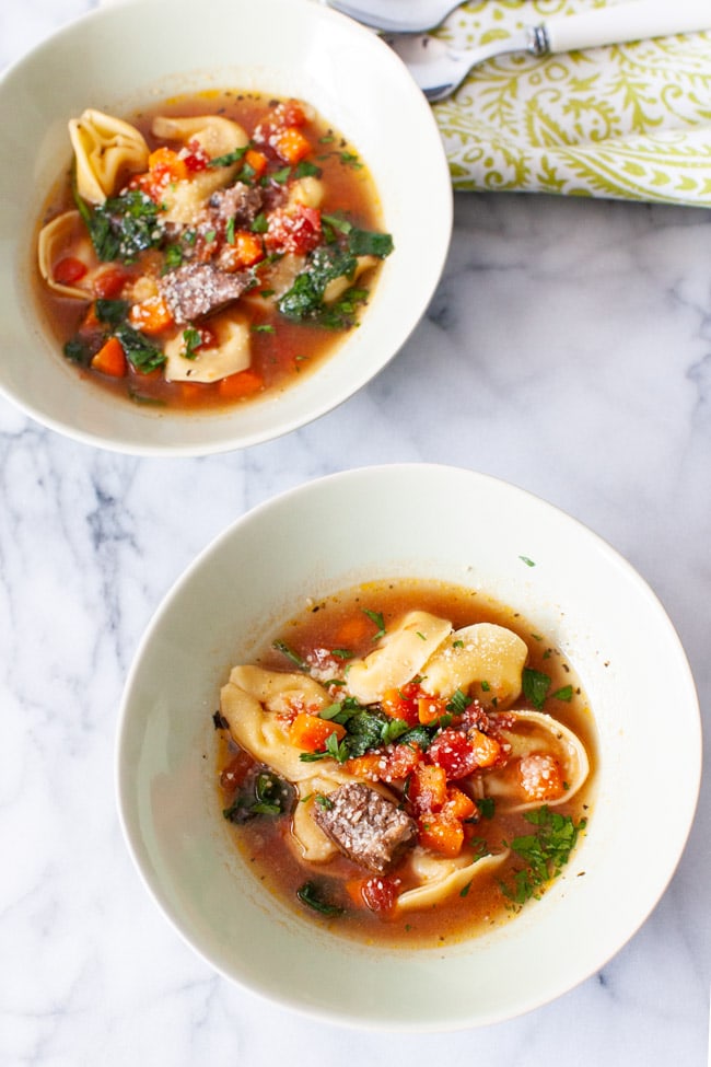 Instant Pot Tortellini Soup from thelittlekitchen.net Two white bowls of Beet Tortellini Soup with a green napkin and spoons in the background.