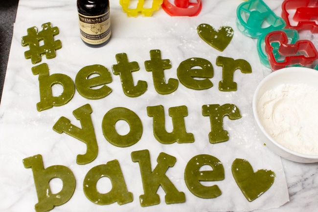 Matcha Cookies from thelittlekitchen.net Matcha Cookie dough cut to spell #betteryourbake with bottle of vanilla, cookie cutters, and bowl of flour in background from thelittlekitchen.net