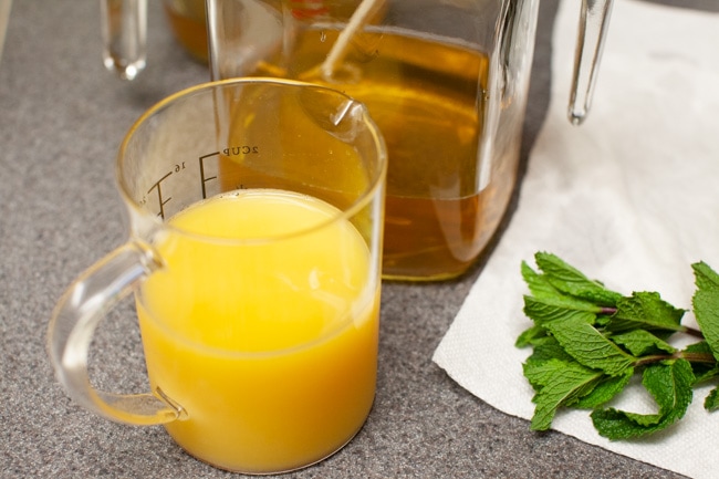Orange Mint Tea from thelittlekitchen.net orange juice in a measuring cup, tea in a jug and mint leaves on a counter