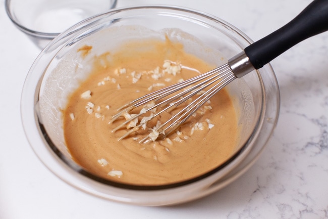 How to Make Peanut Sauce from thelittlekitchen.net almost done making peanut sauce in a glass Pyrex bowl with a small whisk