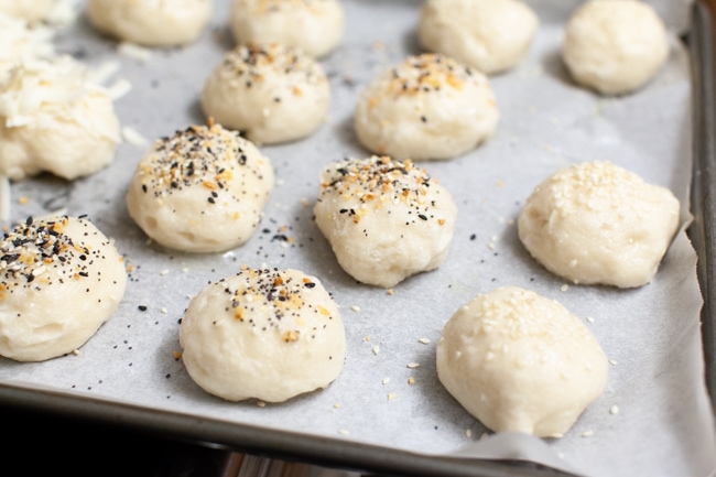 Stuffed Bagel Bites from thelittlekitchen.net stuffed bagel bites with toppings (sesame seed, everything bagel seasoning) on a parchment paper lined baking sheet
