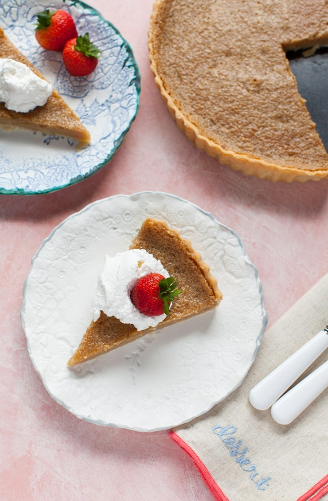 Slice of Sugar Pie on a white plate, topped with whipped cream and strawberry Slice of Sugar Pie on a white plate, topped with whipped cream and strawberry