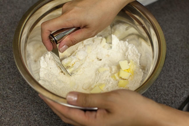 Hands using a pastry blender to cut butter into flour mixture for pie crust Hands using a pastry blender to cut butter into flour mixture for pie crust