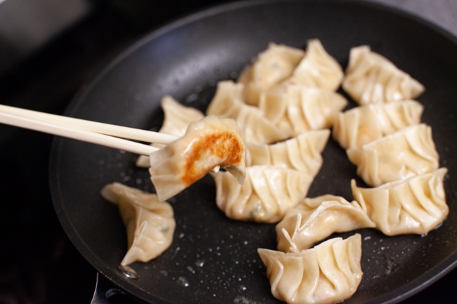 Vegetarian Dumplings from thelittlekitchen.net Vegetarian Dumpling with browned bottom, being picked up from skillet with chopsticks from thelittlekitchen.net